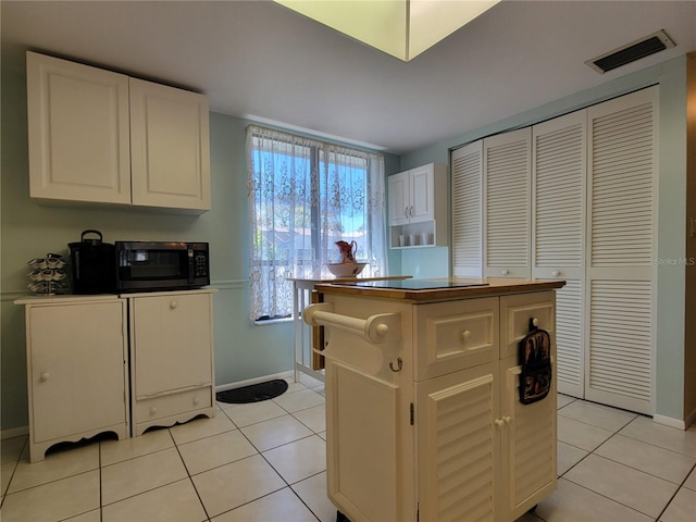 kitchen featuring white cabinets, light tile patterned floors, and visible vents