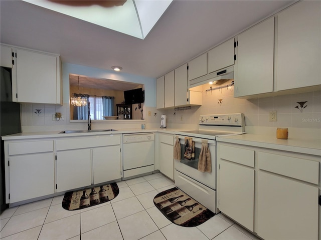 kitchen featuring white appliances, light tile patterned floors, a sink, under cabinet range hood, and tasteful backsplash