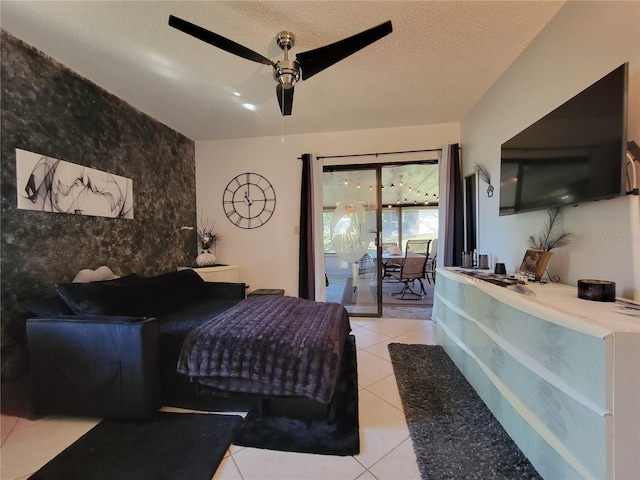 bedroom with a ceiling fan, access to outside, a textured ceiling, light tile patterned floors, and an accent wall