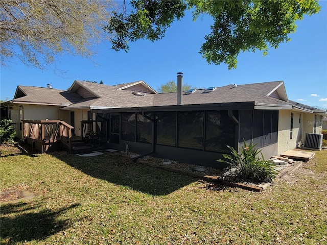 rear view of house featuring a deck, a sunroom, a yard, cooling unit, and a shingled roof