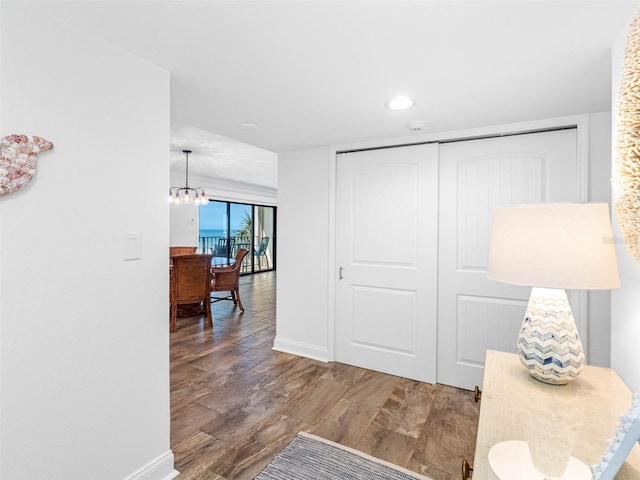 interior space featuring a notable chandelier, wood finished floors, and baseboards