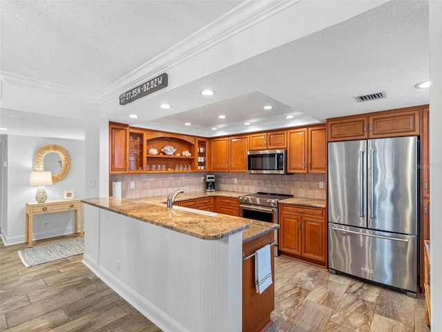 kitchen with light stone counters, brown cabinetry, open shelves, a sink, and stainless steel appliances