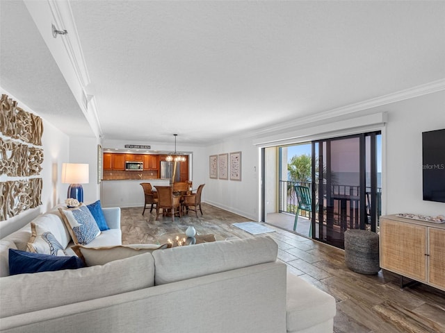 living area featuring a notable chandelier, a textured ceiling, crown molding, and baseboards