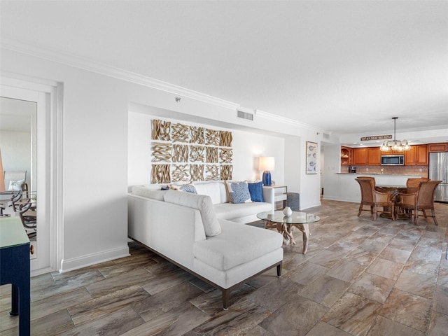 living room with visible vents, baseboards, a chandelier, and crown molding