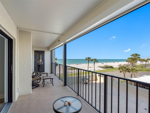 balcony featuring a view of the beach and a water view