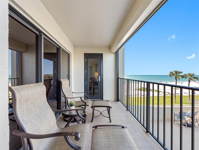 balcony with a water view and a view of the beach