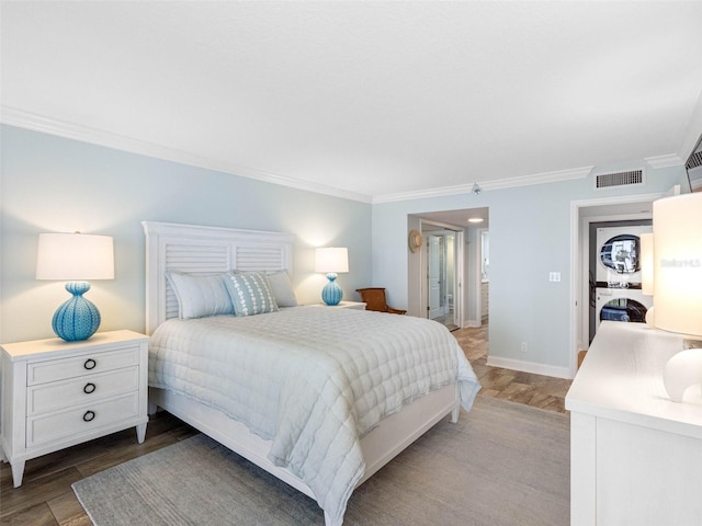 bedroom featuring baseboards, wood finished floors, visible vents, and ornamental molding