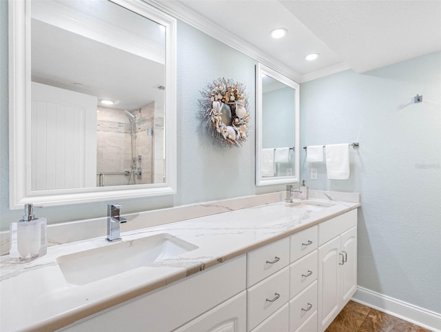 full bath featuring double vanity, baseboards, a tile shower, and a sink