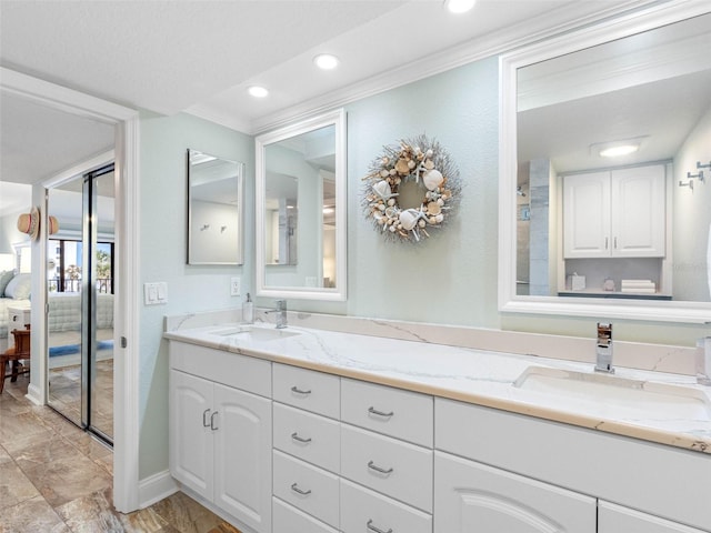 full bathroom featuring double vanity, connected bathroom, crown molding, and a sink