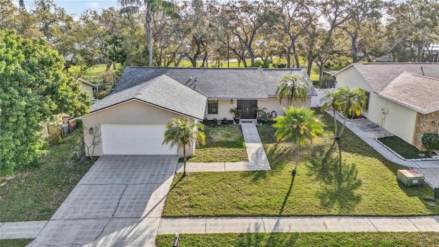 ranch-style home with stucco siding, driveway, a front lawn, an attached garage, and a shingled roof