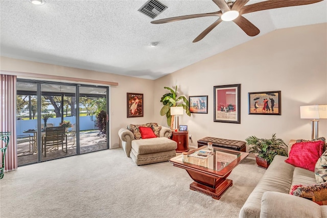 carpeted living room with ceiling fan, vaulted ceiling, visible vents, and a textured ceiling