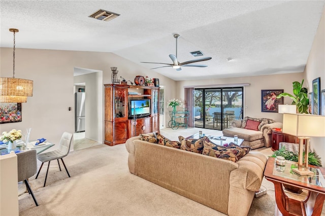 living room featuring a ceiling fan, visible vents, lofted ceiling, a textured ceiling, and light carpet