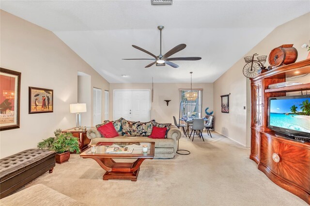 living area featuring lofted ceiling, ceiling fan with notable chandelier, and carpet floors