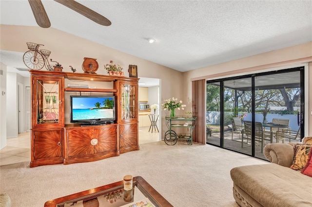 tiled living room featuring a textured ceiling, a ceiling fan, lofted ceiling, and carpet floors