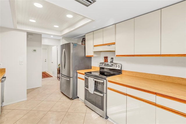 kitchen with under cabinet range hood, a tray ceiling, recessed lighting, stainless steel appliances, and light countertops