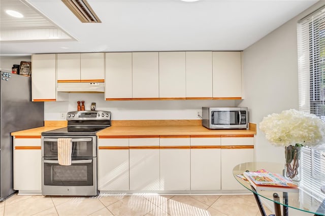 kitchen with under cabinet range hood, stainless steel appliances, light tile patterned flooring, and light countertops