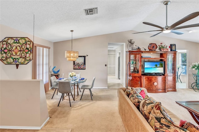 living area featuring visible vents, ceiling fan, light colored carpet, vaulted ceiling, and a textured ceiling