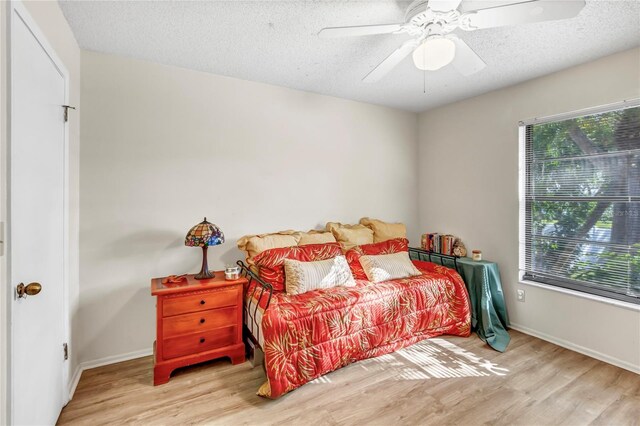 bedroom with ceiling fan, wood finished floors, baseboards, and a textured ceiling