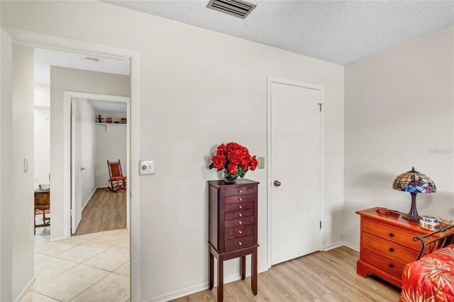 living area with visible vents, light wood-style flooring, and a textured ceiling