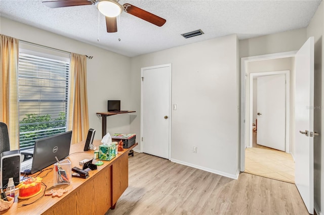 office area featuring visible vents, baseboards, ceiling fan, light wood-style flooring, and a textured ceiling