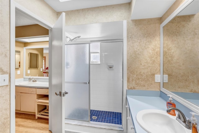 bathroom featuring wood finished floors, a stall shower, and vanity