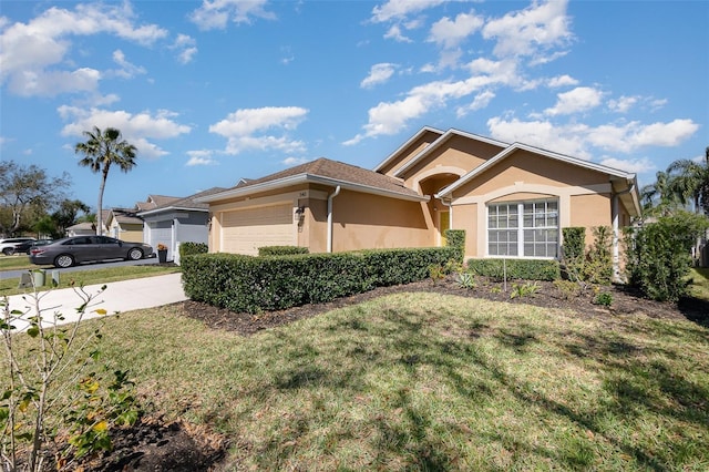 view of front of home featuring a front yard, an attached garage, driveway, and stucco siding