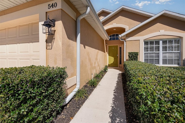 property entrance featuring an attached garage and stucco siding