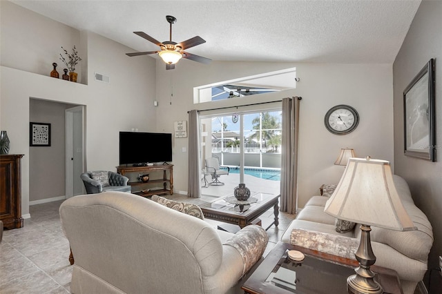 living area featuring visible vents, a ceiling fan, a textured ceiling, baseboards, and lofted ceiling