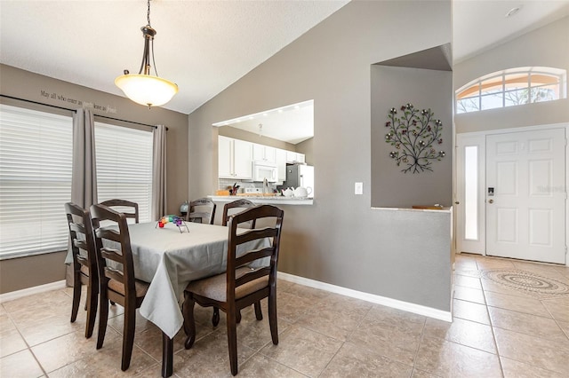 dining space featuring light tile patterned floors, baseboards, and vaulted ceiling