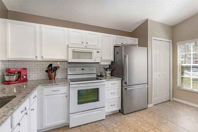 kitchen with light tile patterned floors, decorative backsplash, white appliances, and white cabinetry