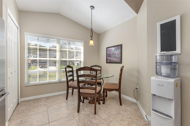 dining area with vaulted ceiling, light tile patterned floors, and baseboards