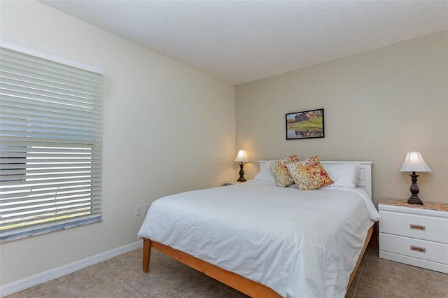 bedroom with light tile patterned floors and baseboards