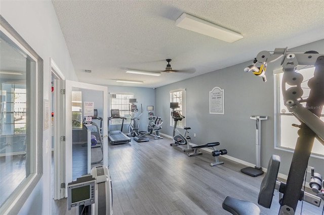 exercise room featuring wood finished floors, baseboards, visible vents, ceiling fan, and a textured ceiling