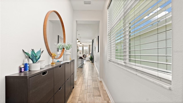 hallway featuring visible vents, baseboards, and wood tiled floor