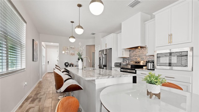 kitchen featuring visible vents, custom range hood, a sink, tasteful backsplash, and stainless steel appliances