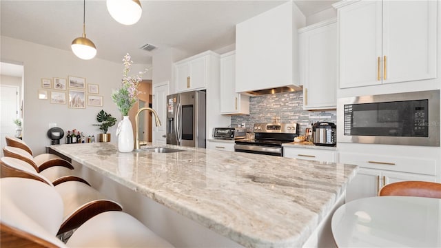 kitchen featuring a breakfast bar area, visible vents, stainless steel appliances, white cabinets, and backsplash