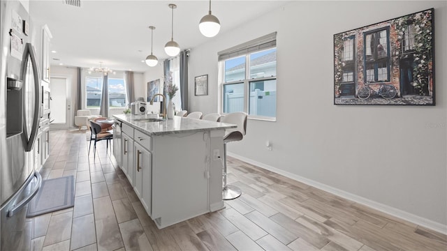 kitchen featuring a breakfast bar, white cabinets, stainless steel fridge with ice dispenser, and a sink