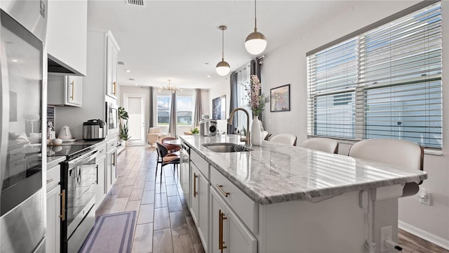 kitchen featuring a kitchen island with sink, appliances with stainless steel finishes, wood finish floors, and a sink