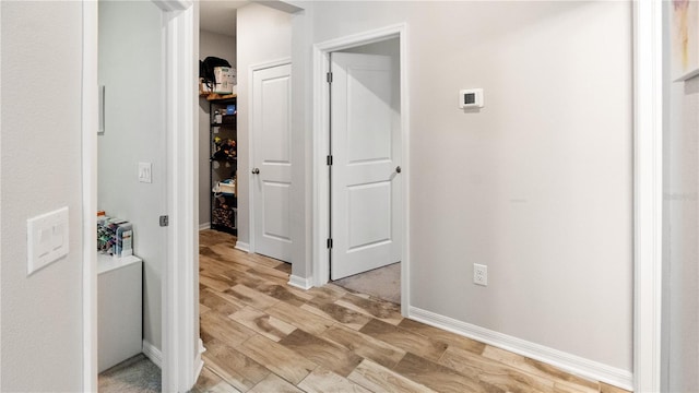 hallway featuring light wood-type flooring and baseboards