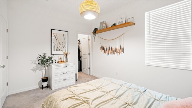 bedroom featuring baseboards, light carpet, and a spacious closet