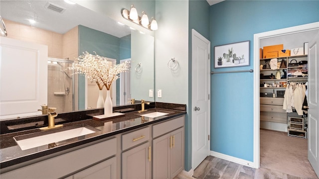 bathroom featuring a sink, visible vents, double vanity, and a shower stall