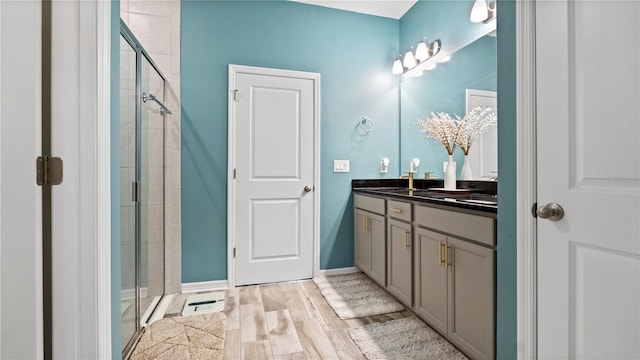 bathroom with vanity, wood finished floors, a stall shower, and baseboards