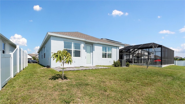 back of house with a lanai, a lawn, a fenced backyard, and stucco siding