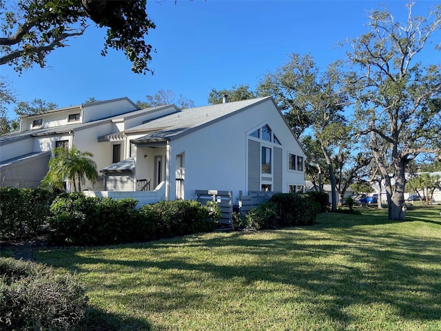 view of side of home with stucco siding and a lawn