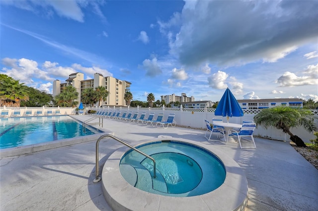 pool with a patio, a community hot tub, and fence