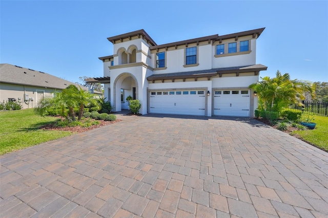 view of front of home with a garage, decorative driveway, fence, and stucco siding