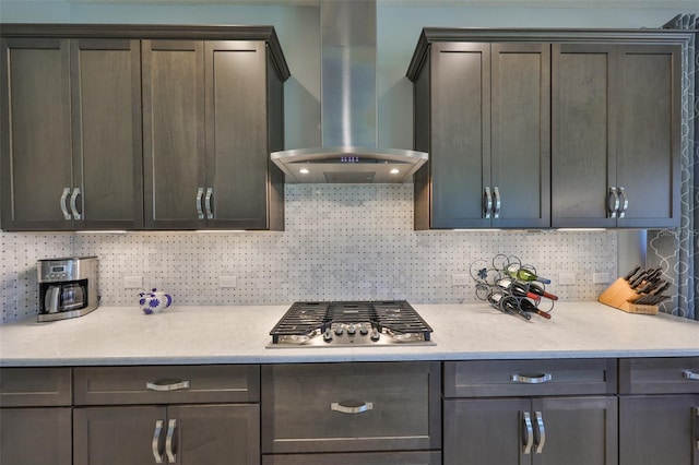 kitchen with stainless steel gas stovetop, light countertops, and wall chimney range hood