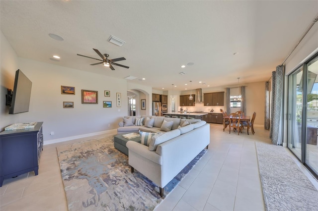 living room with recessed lighting, light tile patterned floors, arched walkways, and visible vents