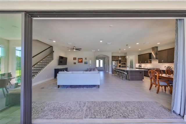 living room featuring stairway, light tile patterned floors, recessed lighting, and arched walkways