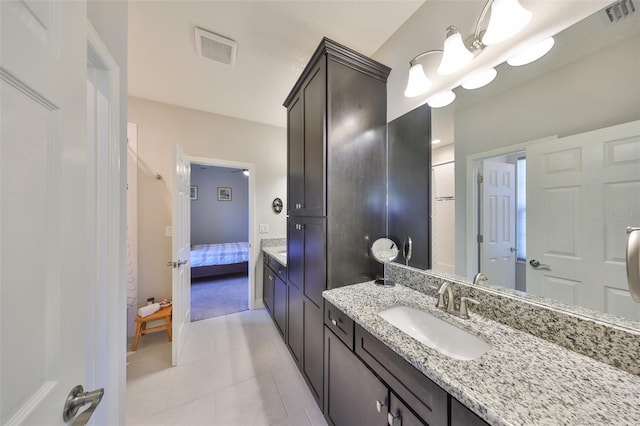 ensuite bathroom featuring vanity, tile patterned floors, visible vents, and connected bathroom